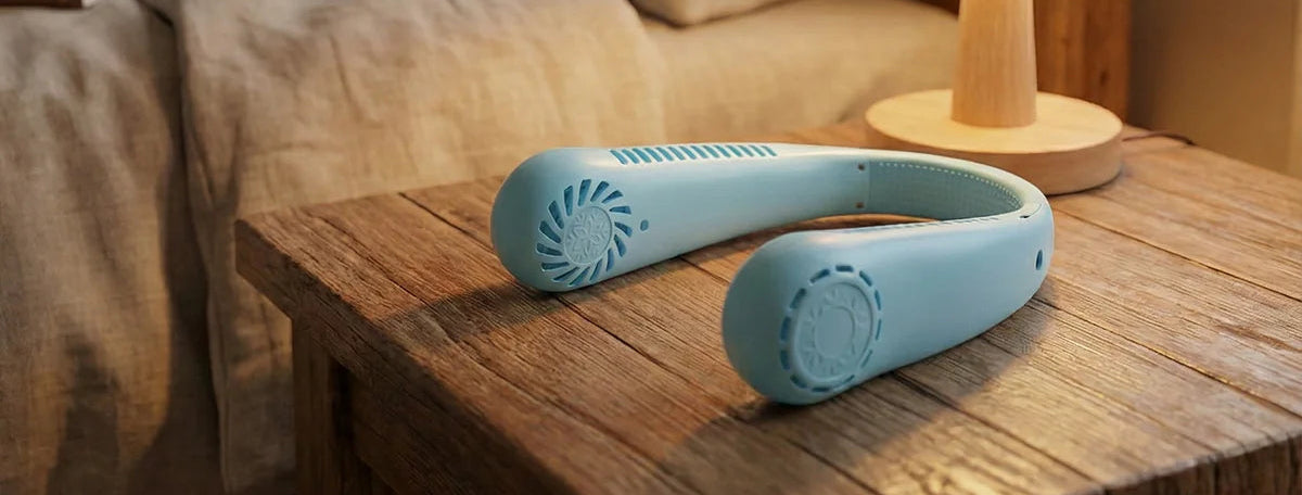Blue handheld massager on a wooden nightstand with a lamp and books in the background.